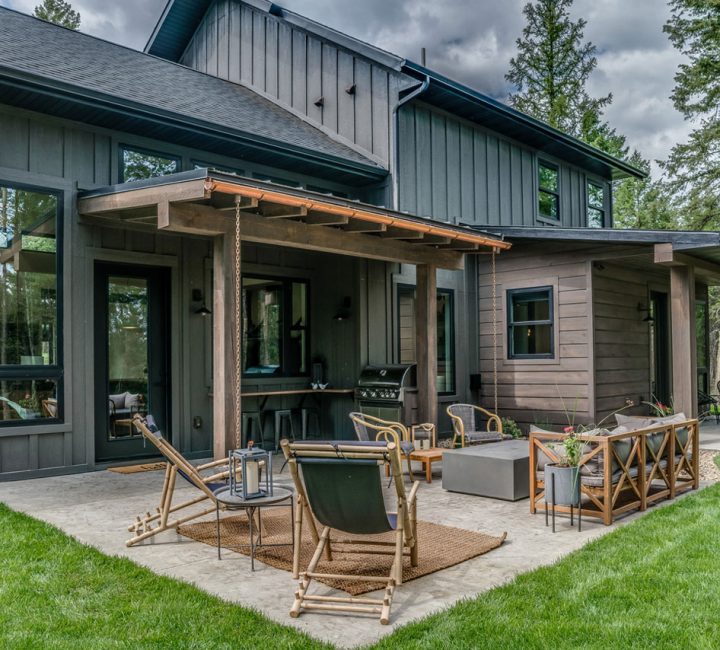 A stylish outdoor living area featuring modern furniture and a cooking area, set against a backdrop of dense trees in a serene environment.