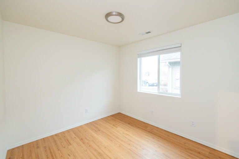 Simple, empty room with white walls, recessed ceiling light, and one window letting in natural light—perfect for staging or personalizing as a bedroom or office.