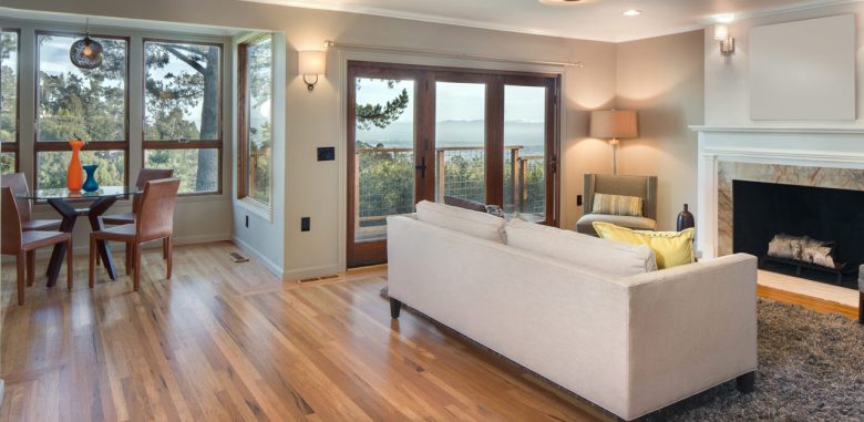 An inviting living and dining area with large windows providing a breathtaking view, featuring wooden floors, contemporary furniture, and subtle decor accents.